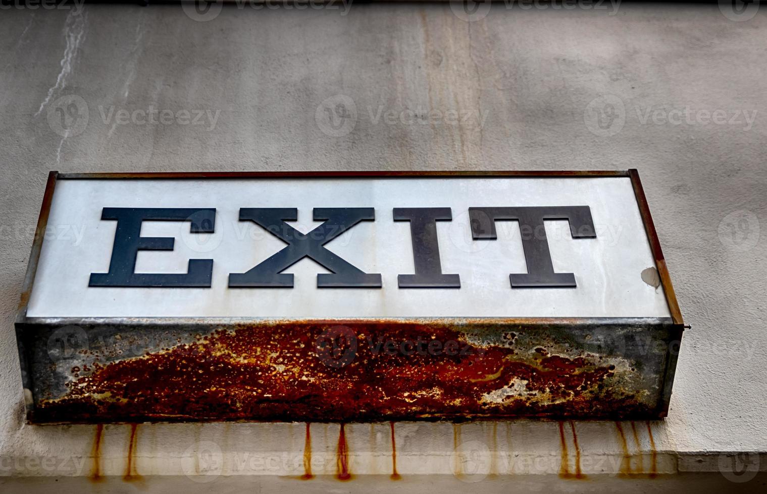 Rusty worn exit sign on a concrete wall photo