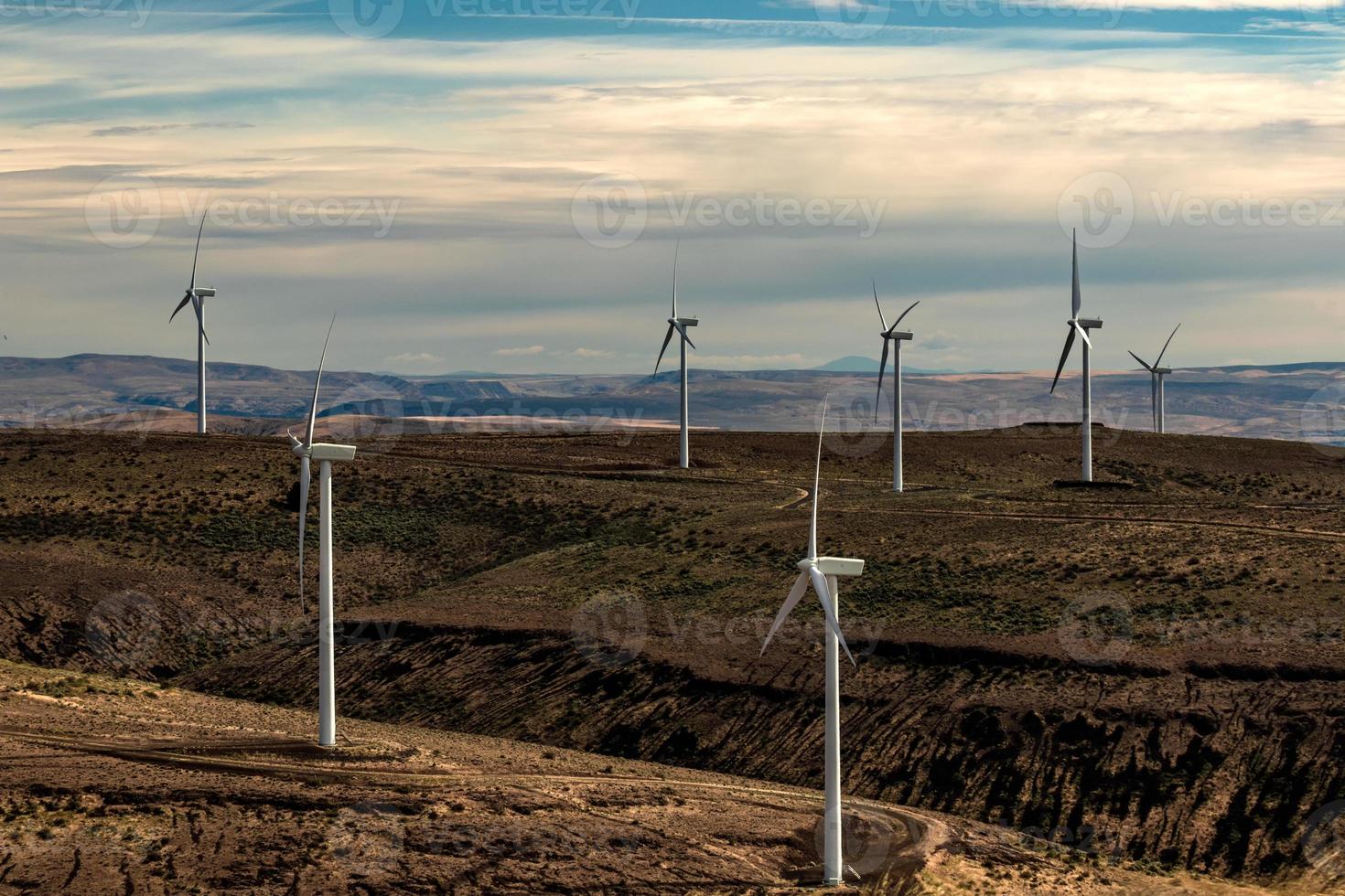 Green sustainable energy windmill power turbine electricity generators on rolling hills with clouds and blue sky photo