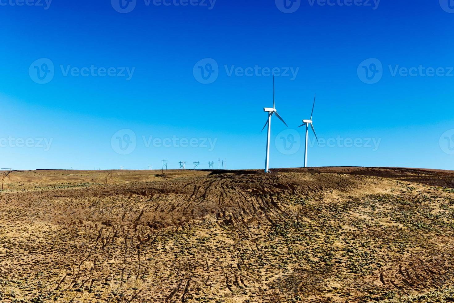 Green sustainable energy windmill power turbine electricity generators on rolling hills with clouds and blue sky photo