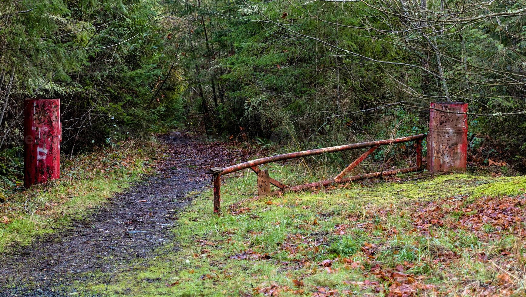 Abandoned red gate on a mountain trail with bullet holes photo