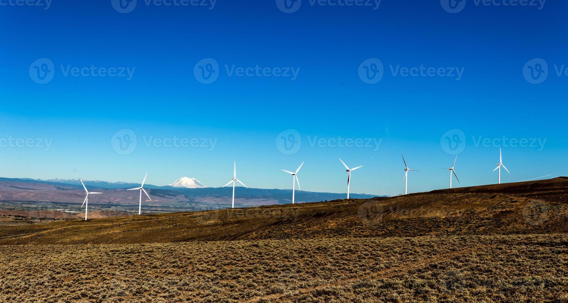 Green sustainable energy windmill power turbine electricity generators on rolling hills with clouds and blue sky photo
