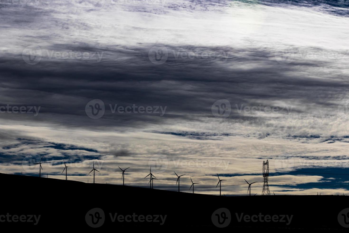 Green sustainable energy windmill power turbine electricity generators on rolling hills with clouds and blue sky photo