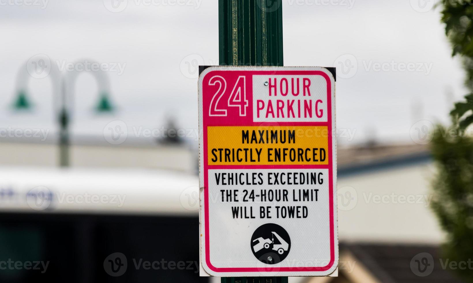 24 hour parking strictly enforced sign on a green post photo