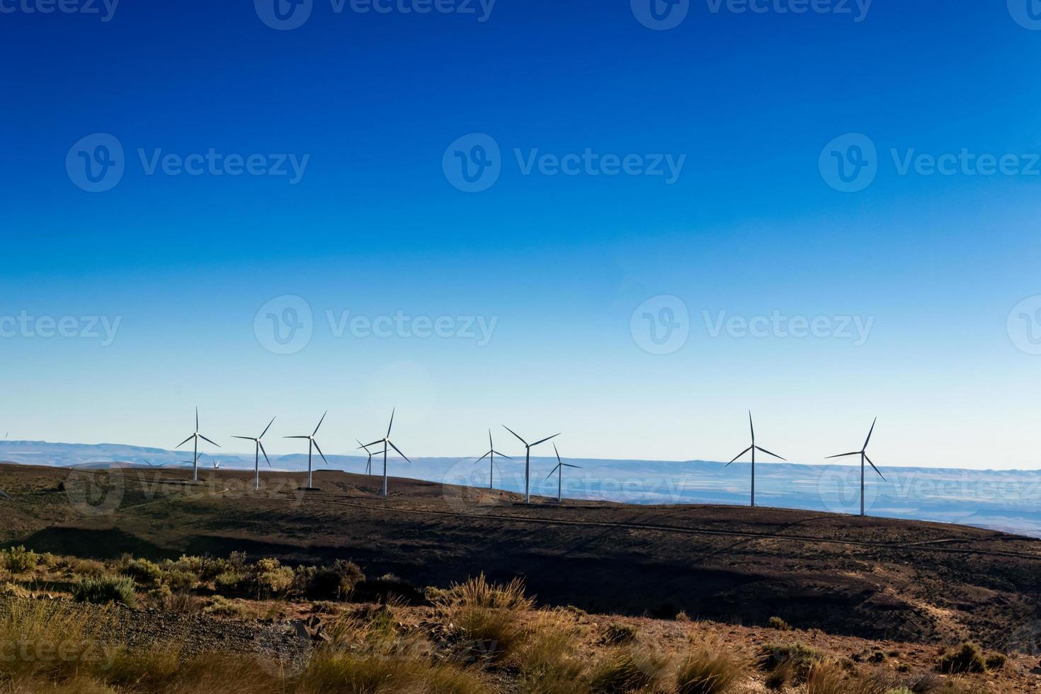 Green sustainable energy windmill power turbine electricity generators on rolling hills with clouds and blue sky photo