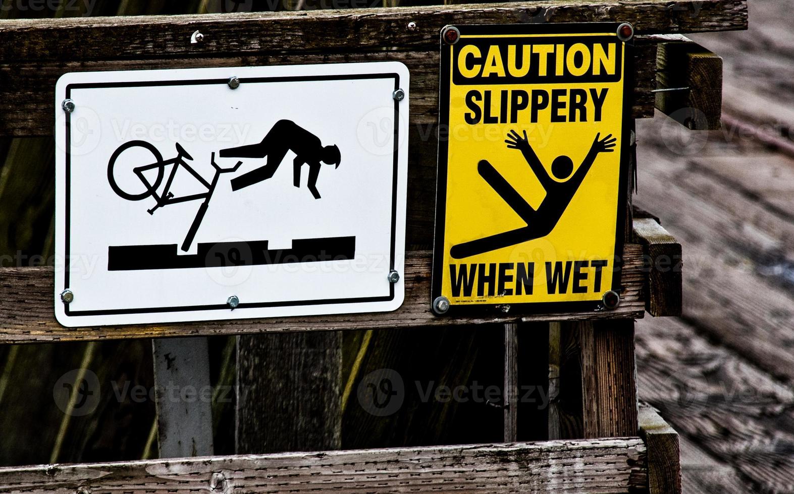 Bicycle and slip fall danger signs on a wooden rail photo