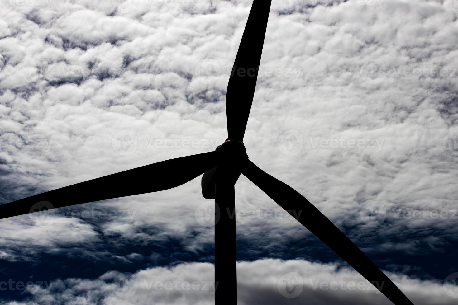 Green sustainable energy windmill power turbine electricity generator on rolling hills with clouds and blue sky photo