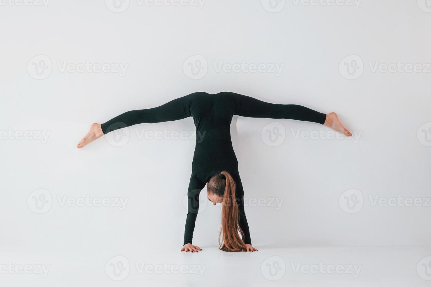 Practice routine. Young woman in sportive clothes doing gymnastics indoors photo