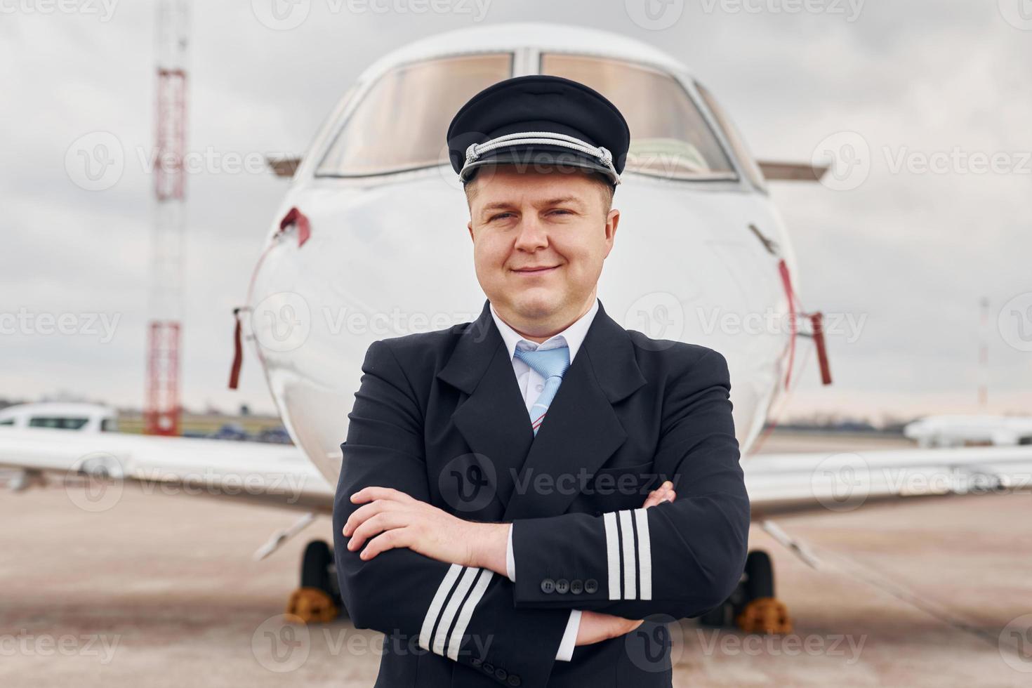 Experienced pilot in uniform standing outside near plane photo