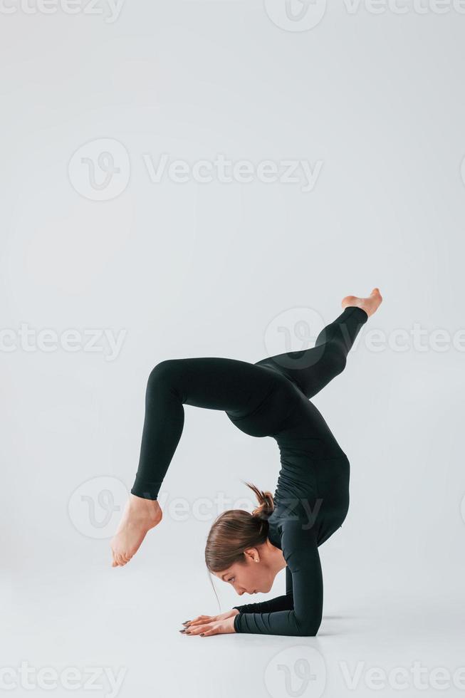 Difficult exercises. Young woman in sportive clothes doing gymnastics indoors photo