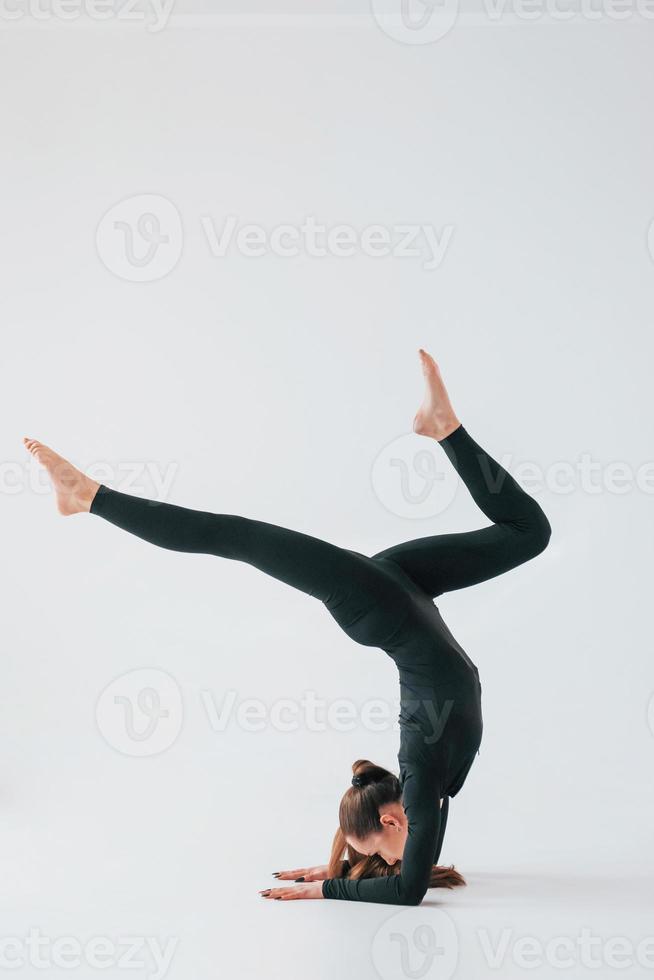 Practice routine. Young woman in sportive clothes doing gymnastics indoors photo