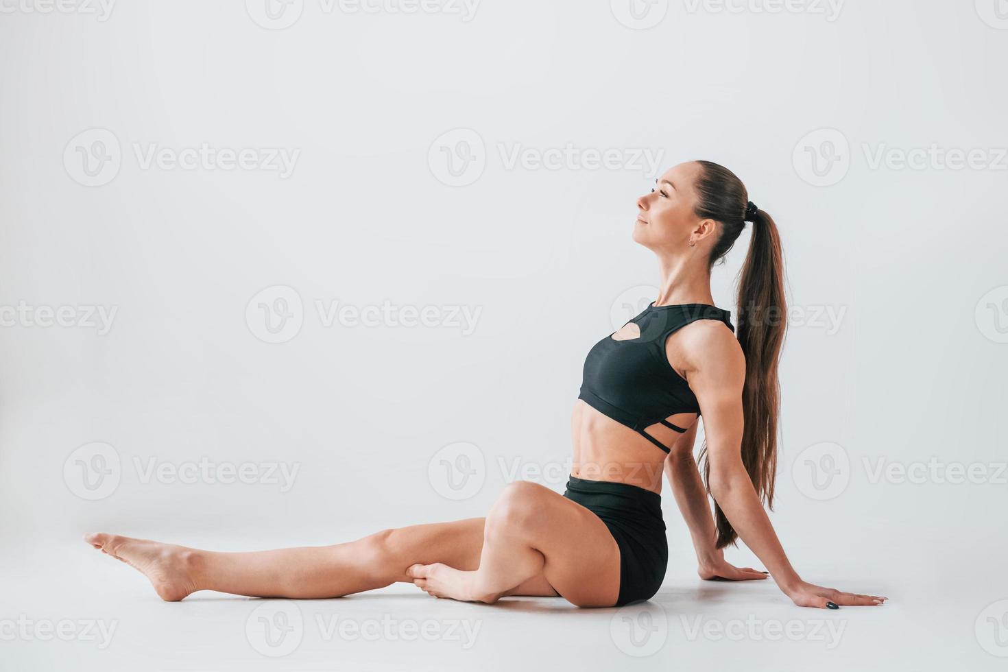 Slim body type. Young woman in sportive clothes doing gymnastics indoors photo