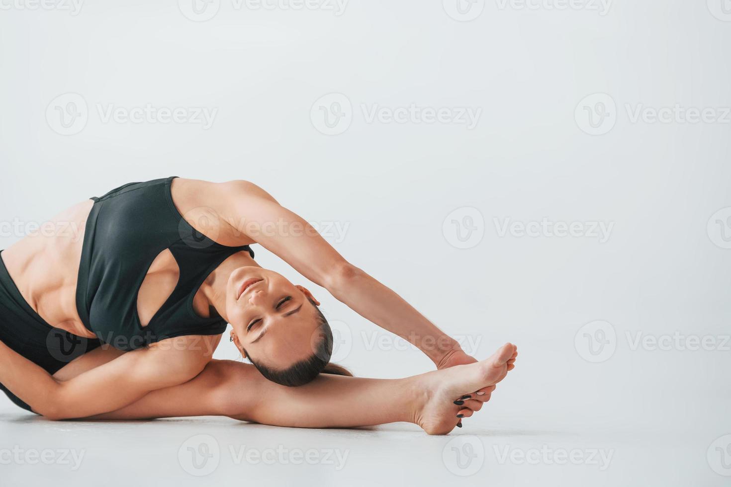 Professional trainer. Young woman in sportive clothes doing gymnastics indoors photo