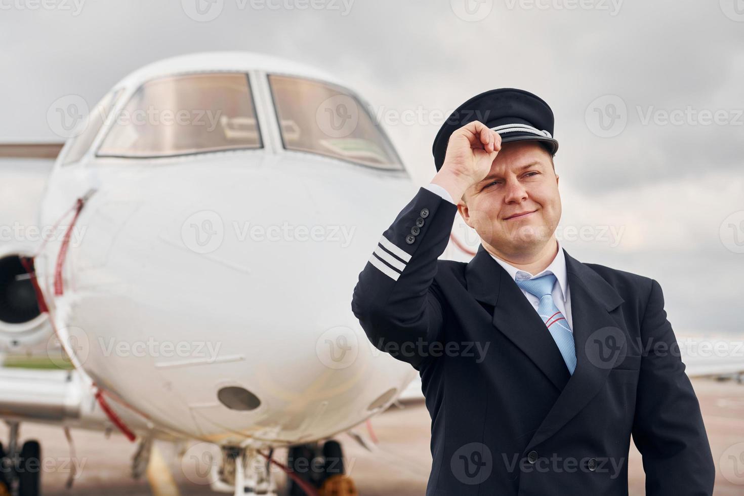 Experienced pilot in uniform standing outside near plane photo