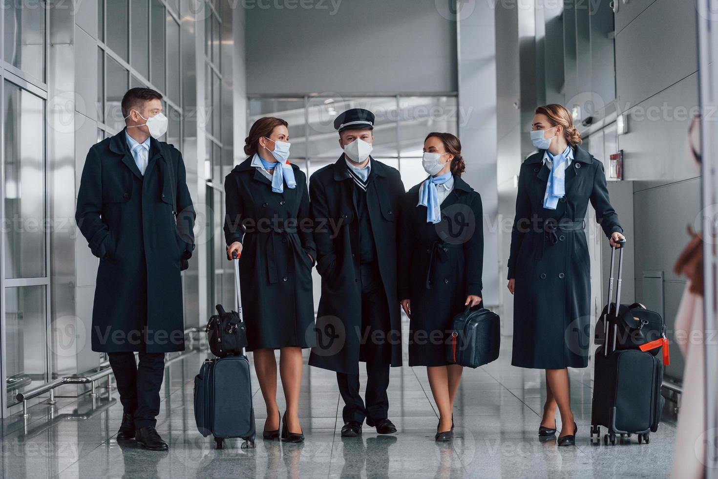 Aircraft crew in work uniform is together outdoors in the airport photo