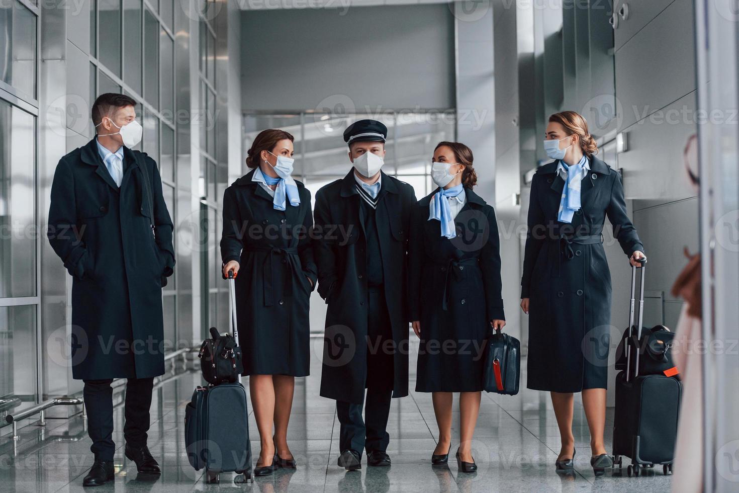 Aircraft crew in work uniform is together outdoors in the airport photo