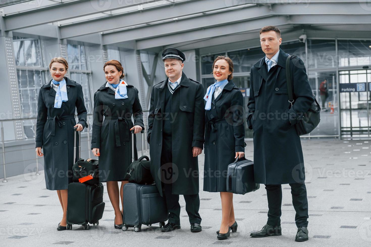 Aircraft crew in work uniform is together outdoors in the airport photo