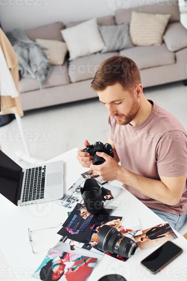 Photographer in casual clothes is working indoors at daytime photo