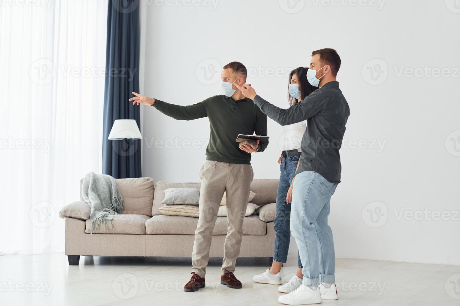 Man helps the young couple in choosing an apartment photo