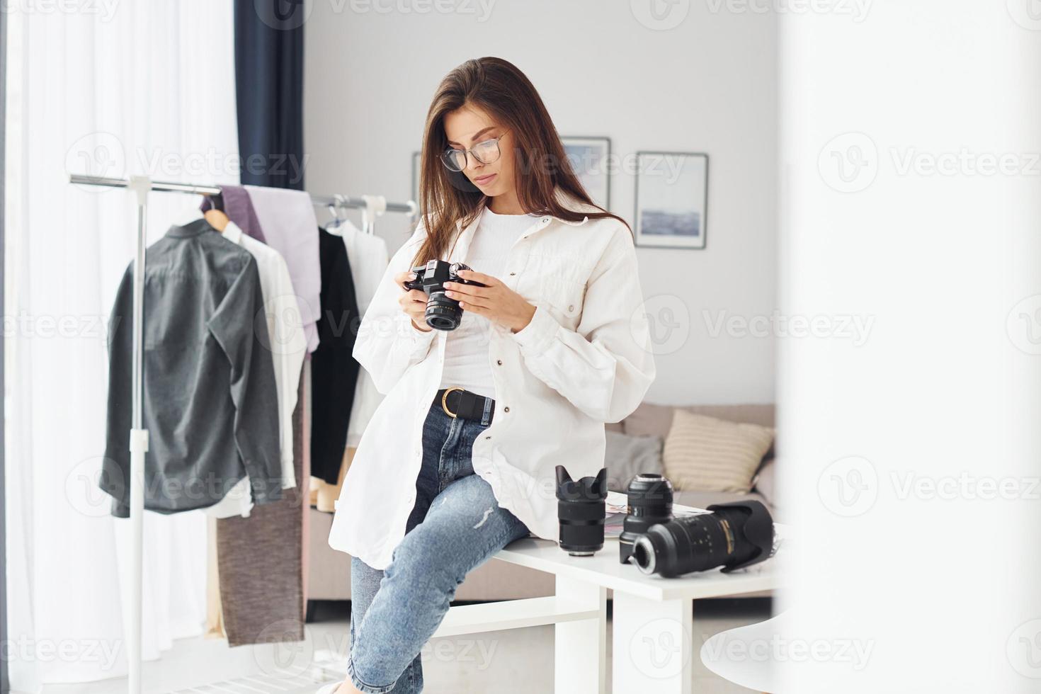 Female photographer in casual clothes is working indoors at daytime photo