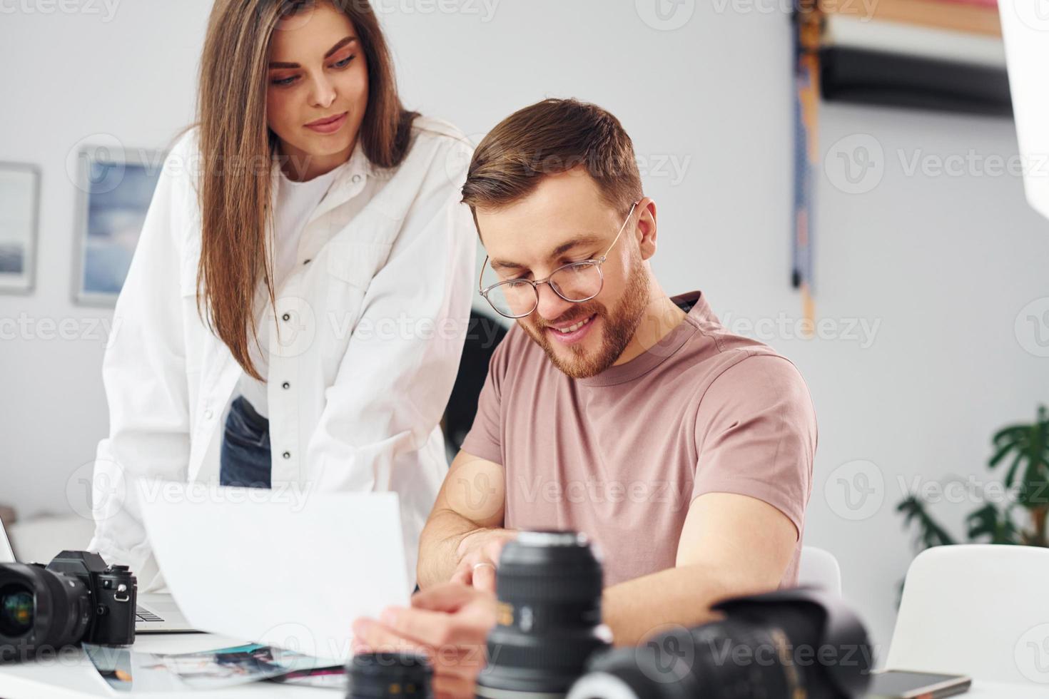 Two photographers in casual clothes is working indoors at daytime photo