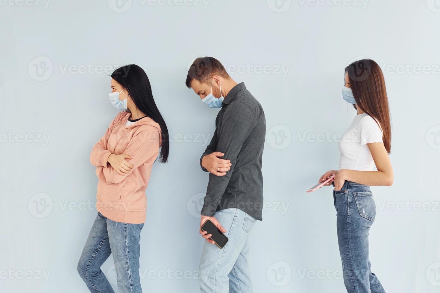 Three people standing together in the studio against white background photo