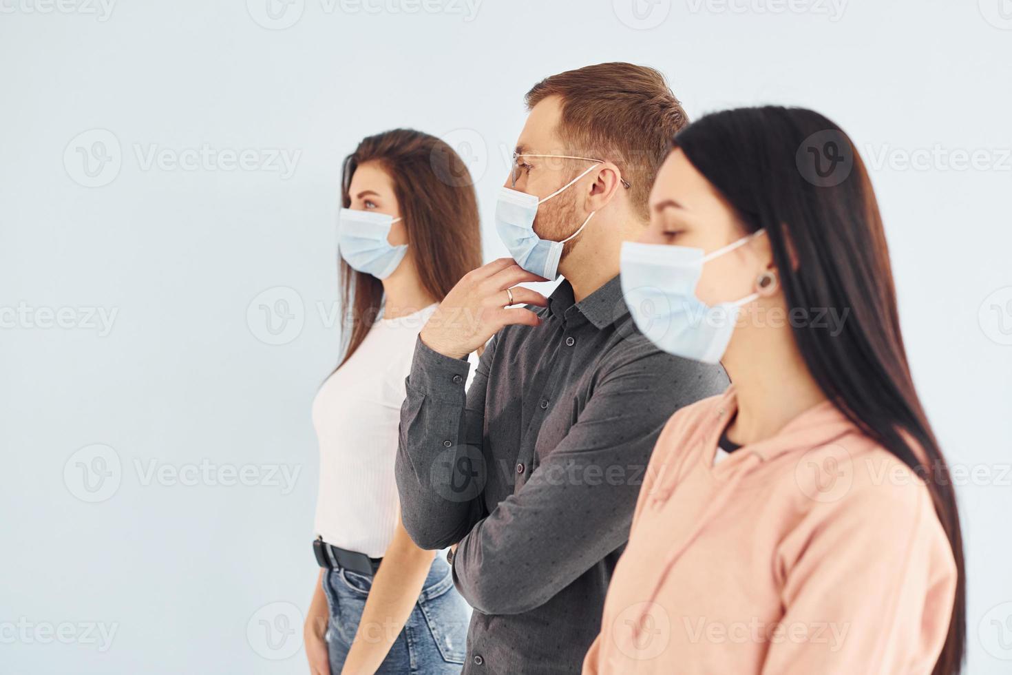Three people standing together in the studio against white background photo