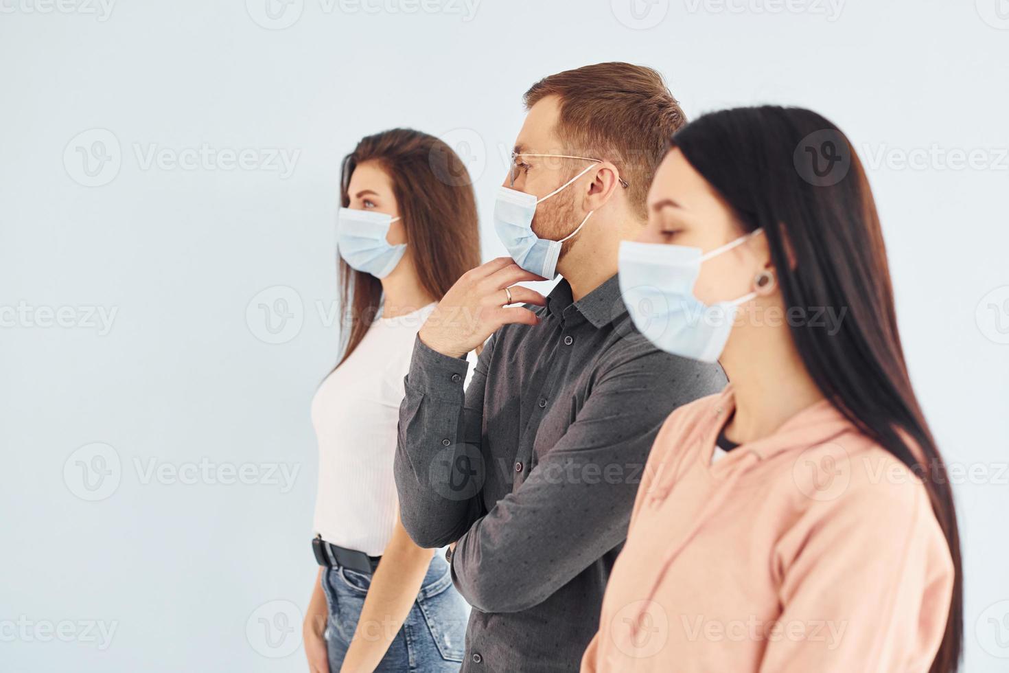 tres personas de pie juntas en el estudio con fondo blanco foto