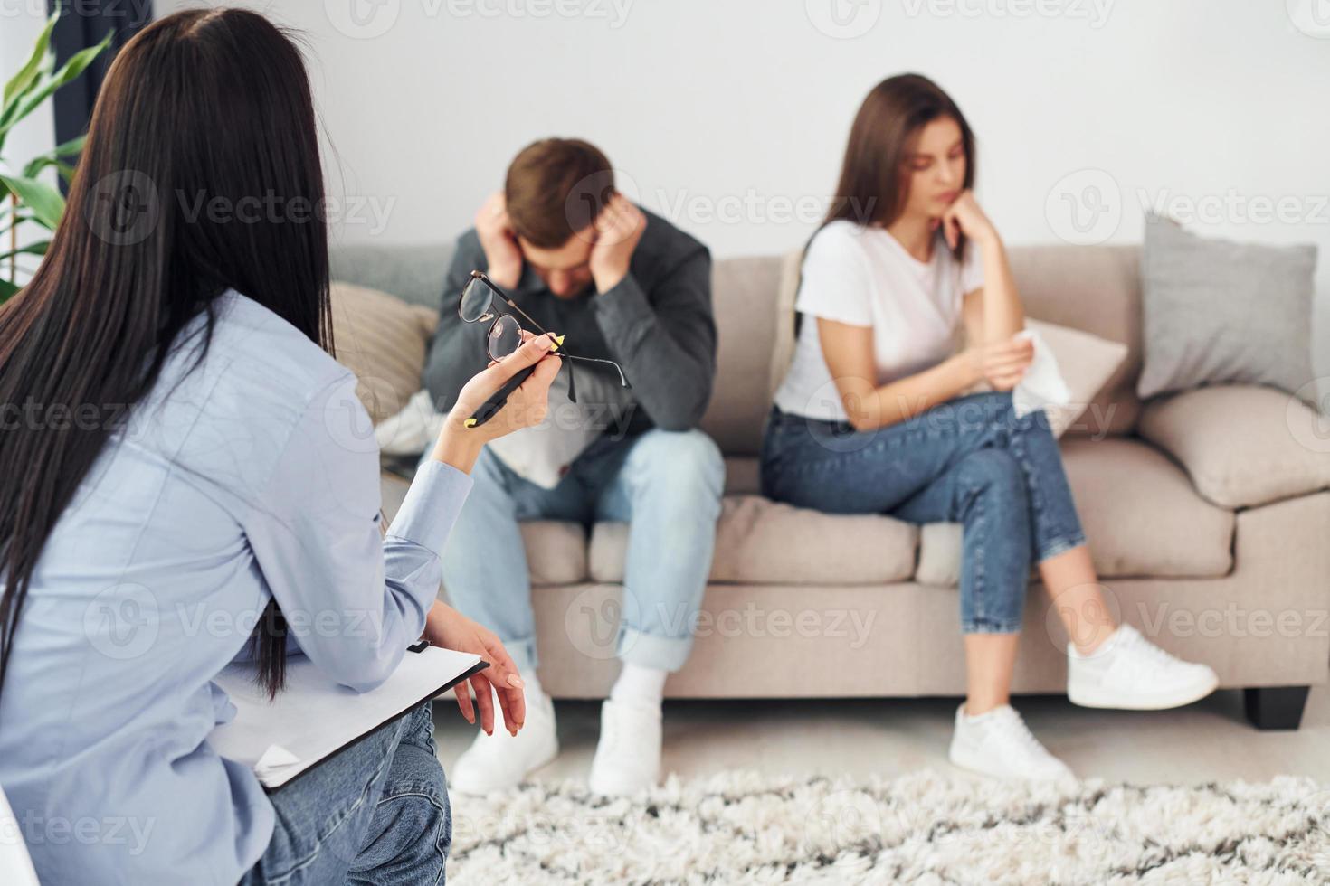 Couple is sitting on the sofa and working with female psychologist photo