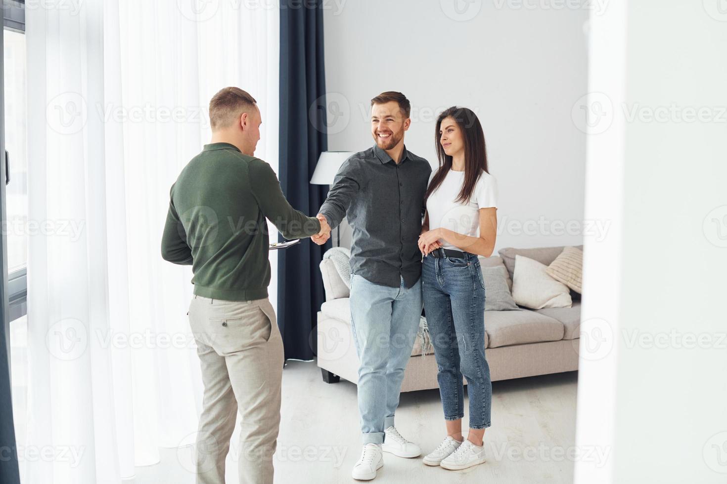 Salesman helps young couple in choosing an apartment. Conception of business and rent photo