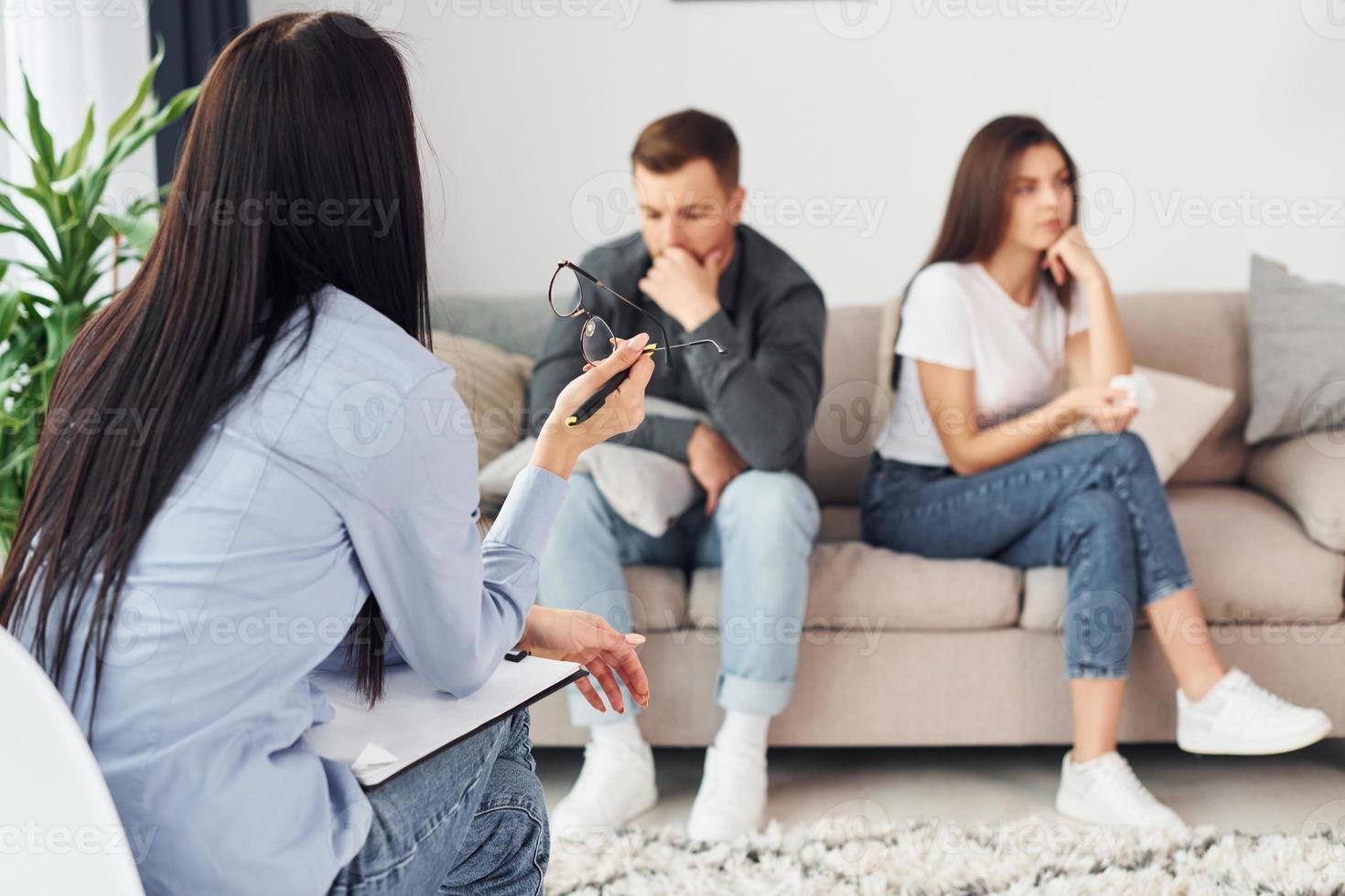 Couple is sitting on the sofa and working with female psychologist photo