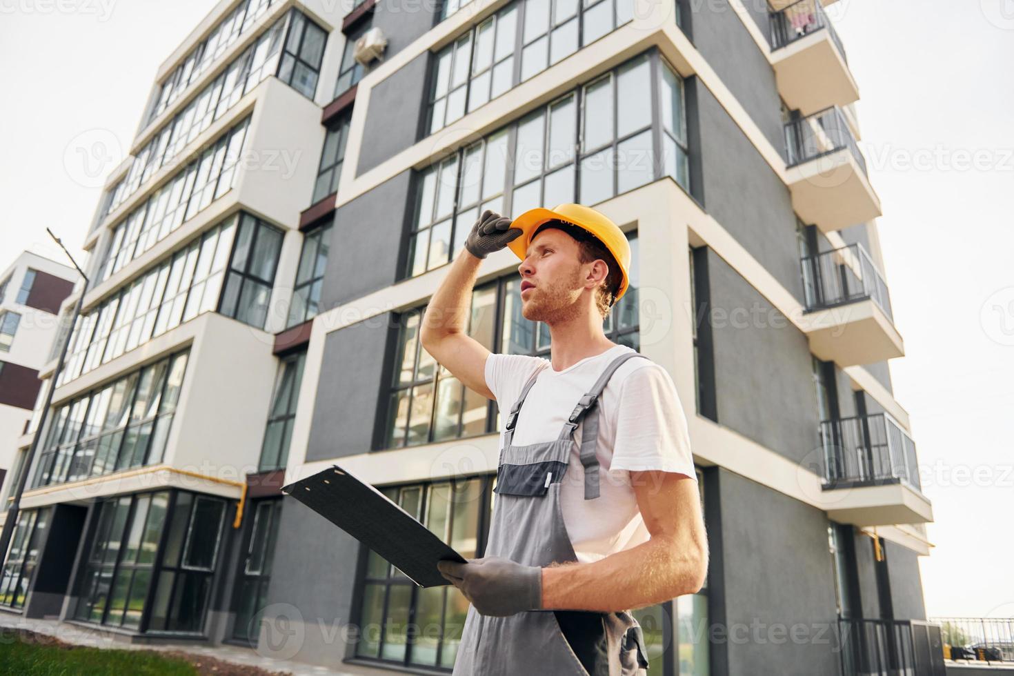 Modern city. Young man working in uniform at construction at daytime photo