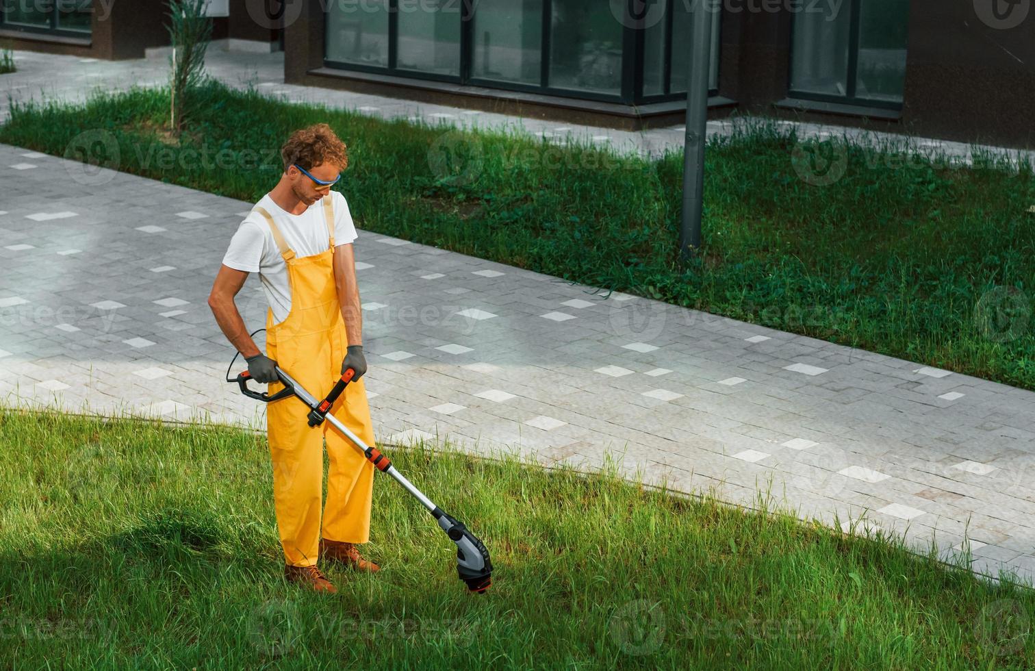 Distant view. Man cut the grass with lawn mover outdoors in the yard photo