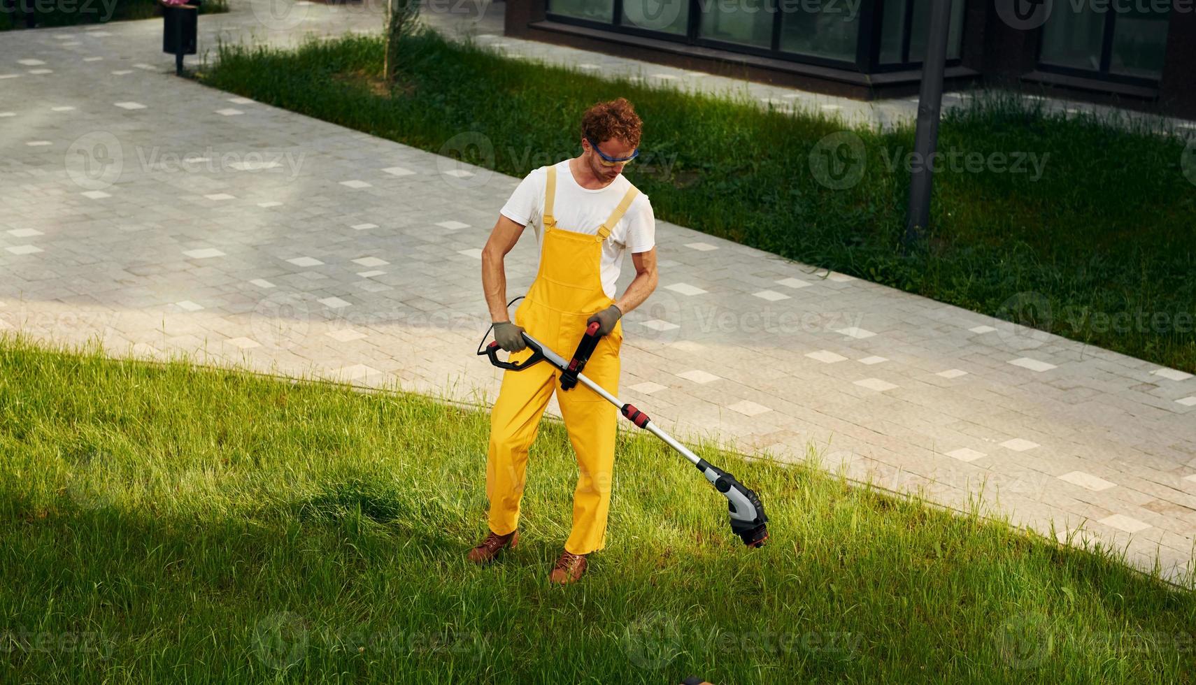Distant view. Man cut the grass with lawn mover outdoors in the yard photo