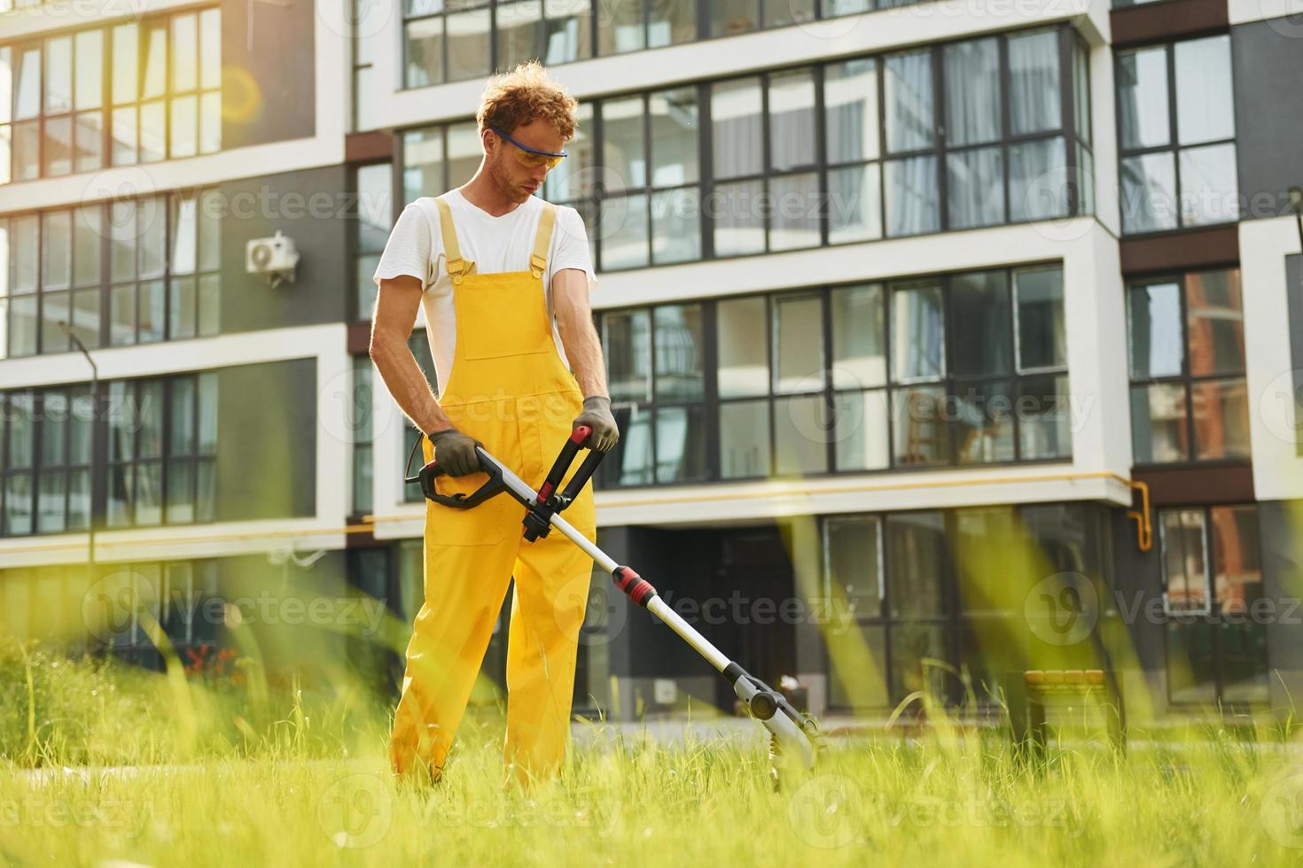 Busy day. Man cut the grass with lawn mover outdoors in the yard photo