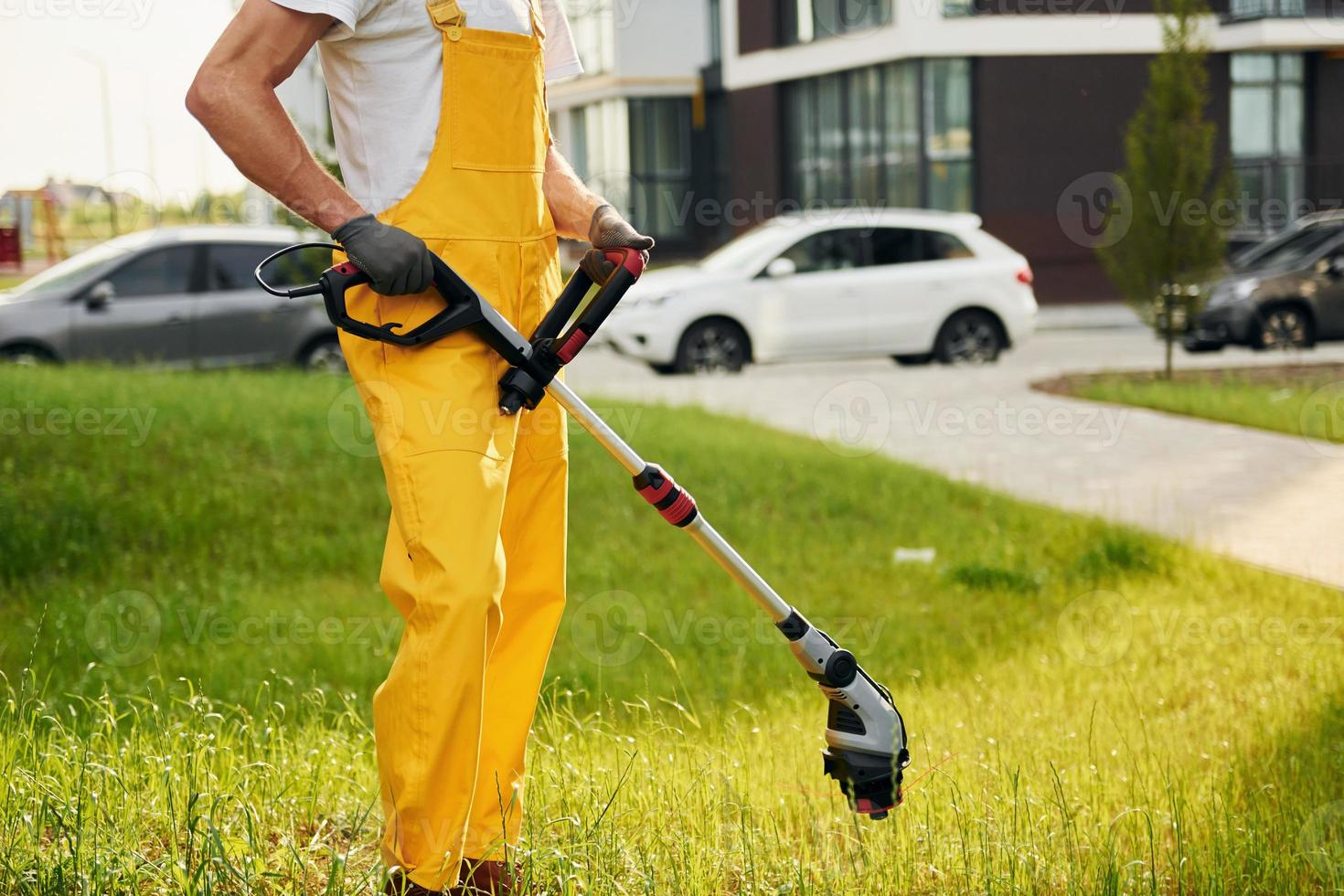Modern buildings. Man cut the grass with lawn mover outdoors in the yard photo