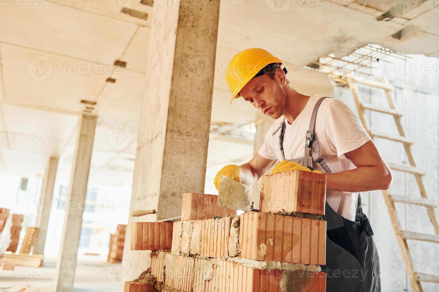 View from the side. Young man working in uniform at construction at daytime photo