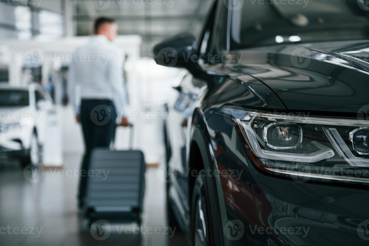 Conception of tourism. Man in formal clothes is with luggage indoors near the car photo