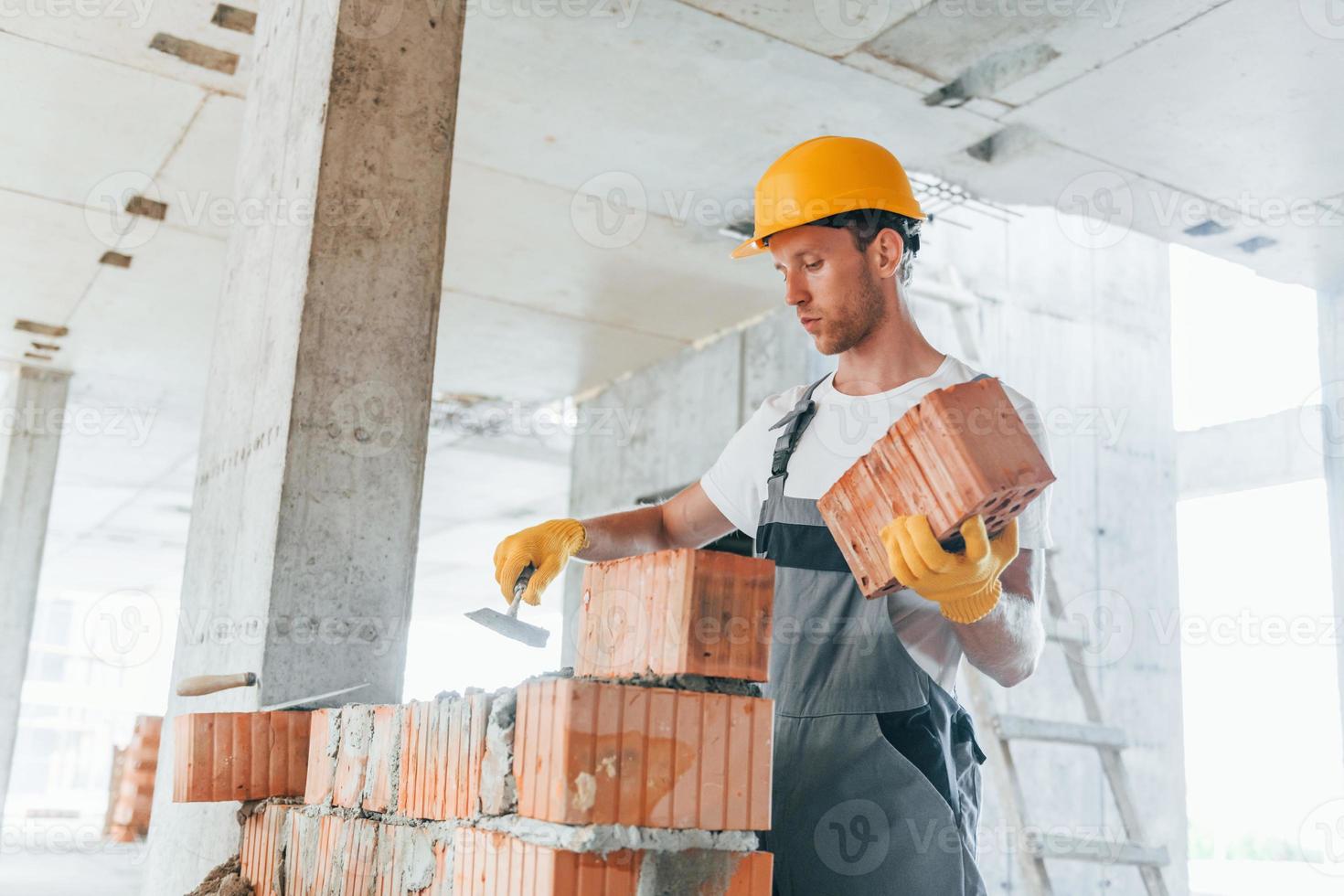 View from the side. Young man working in uniform at construction at daytime photo