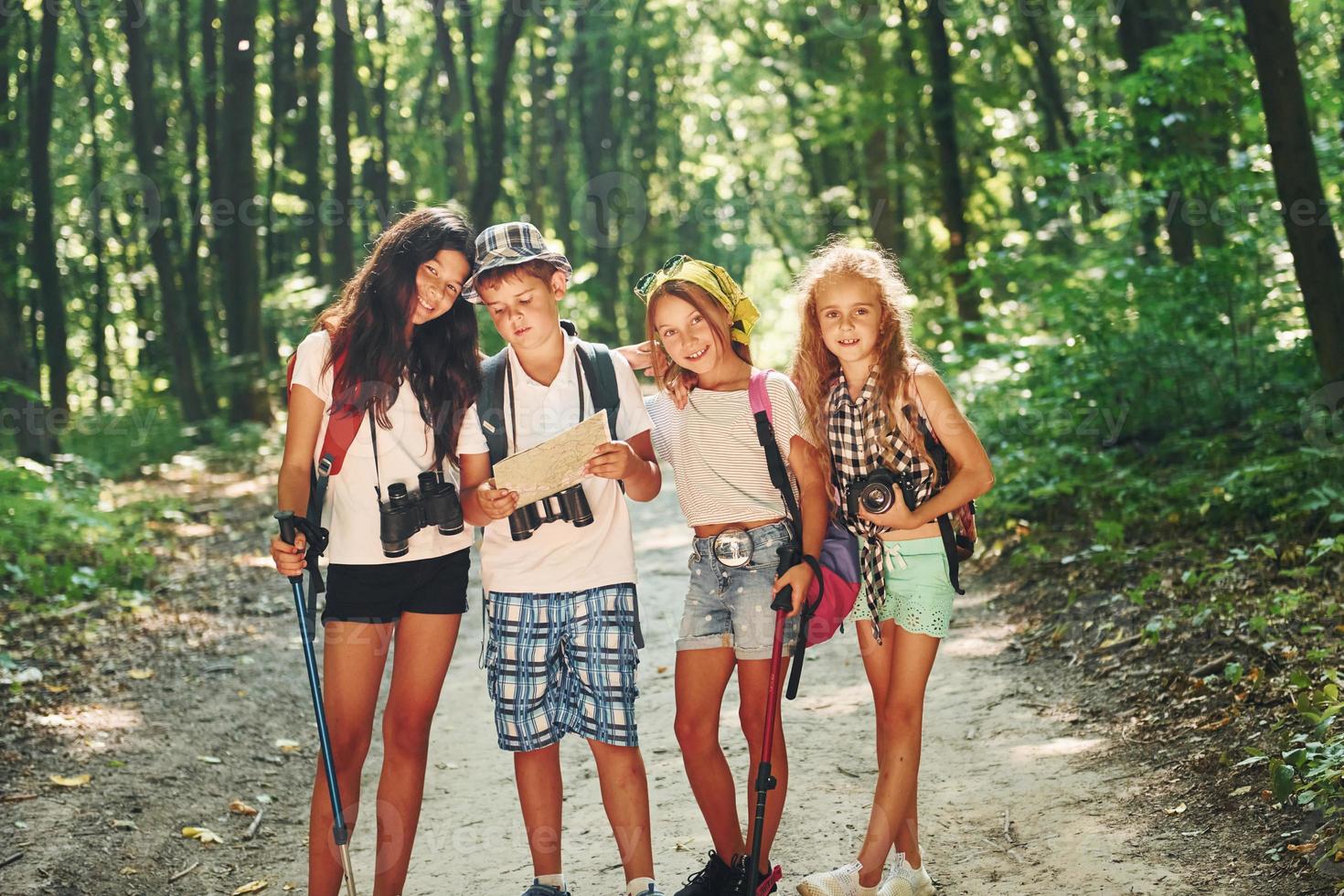 Front view. Kids strolling in the forest with travel equipment photo