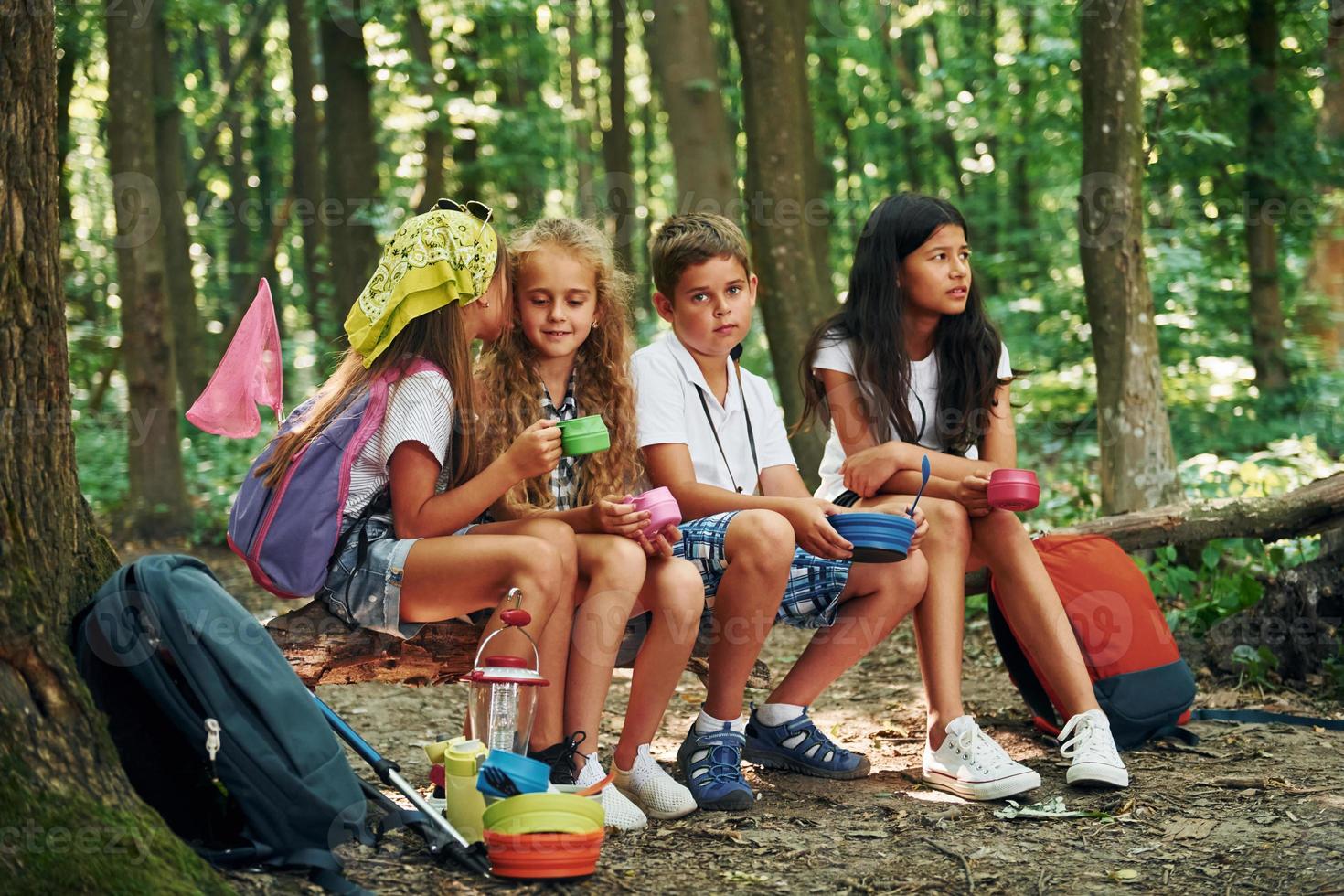 Sitting in the camp. Kids strolling in the forest with travel equipment photo