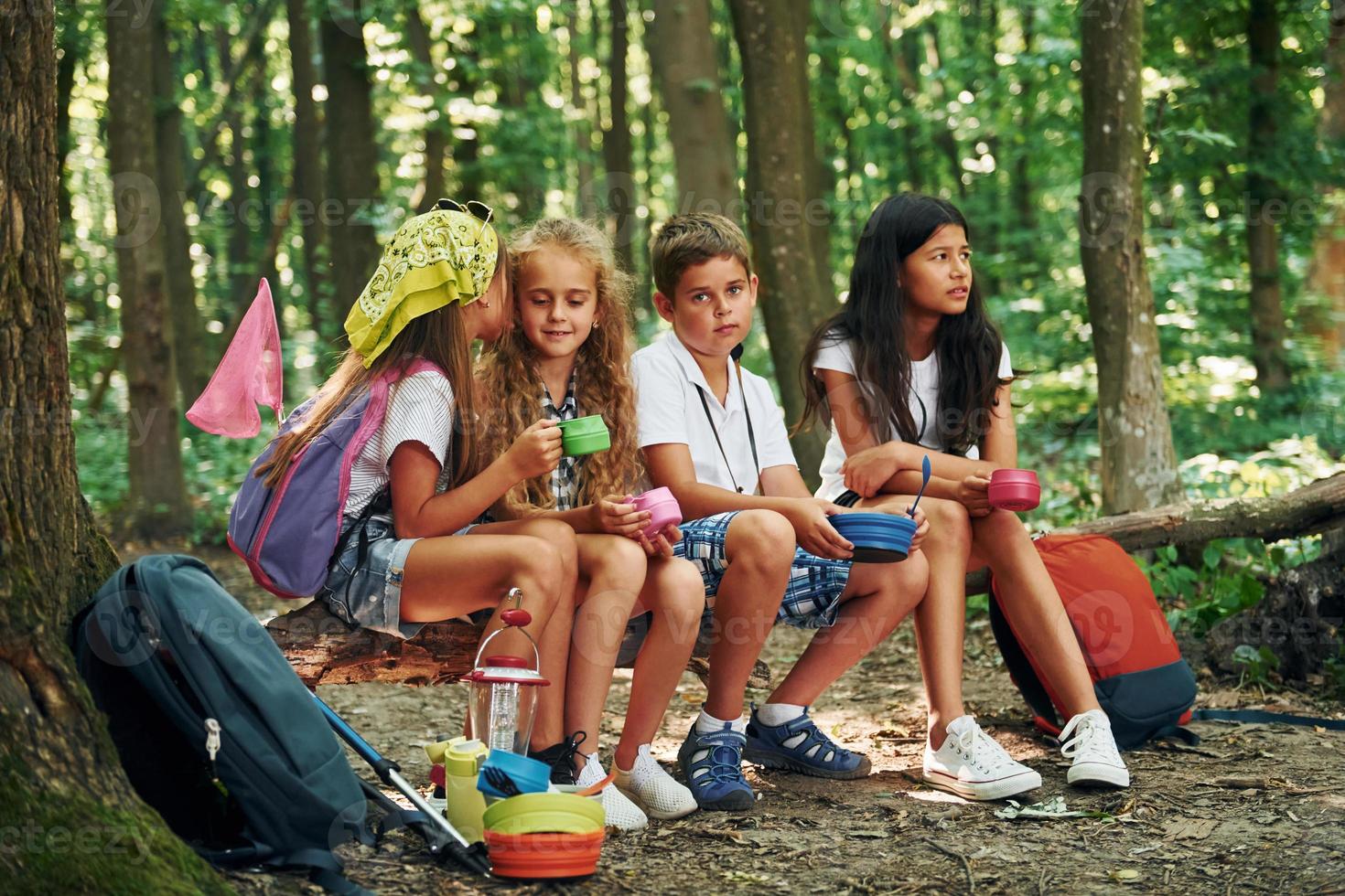 sentado en el campamento. niños paseando por el bosque con equipo de viaje foto