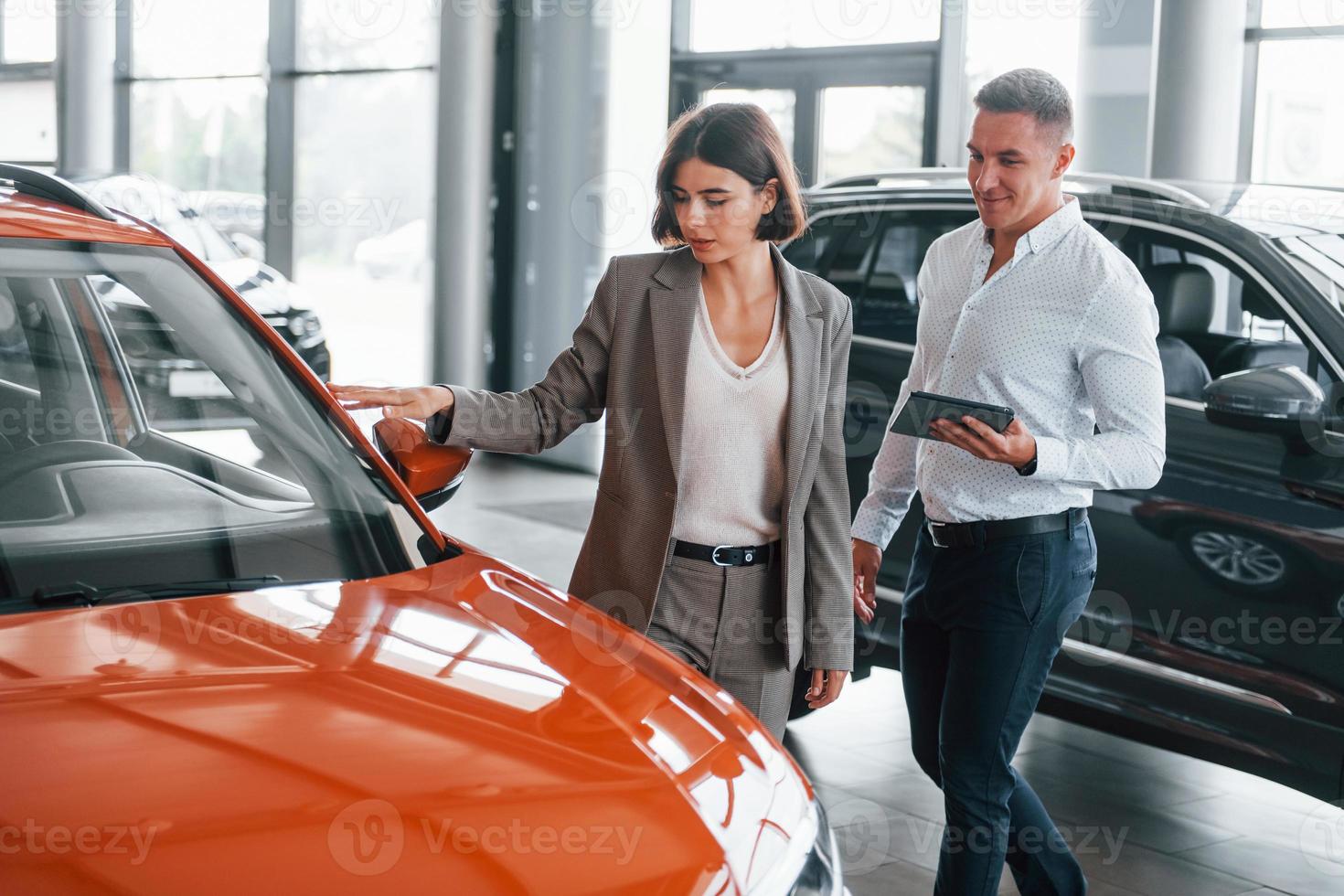 With notepad. Man in formal wear helping customer with choice of the automobile photo