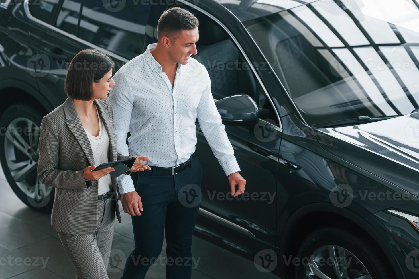 View from above. Man in formal wear helping customer with choice of the automobile photo