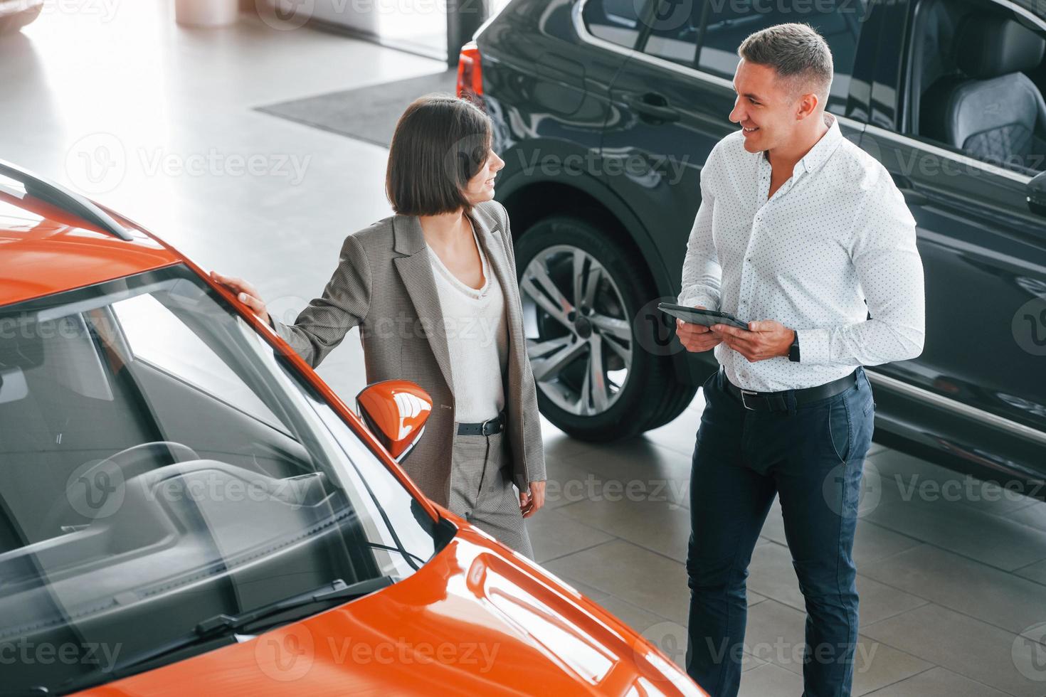 View from above. Man in formal wear helping customer with choice of the automobile photo
