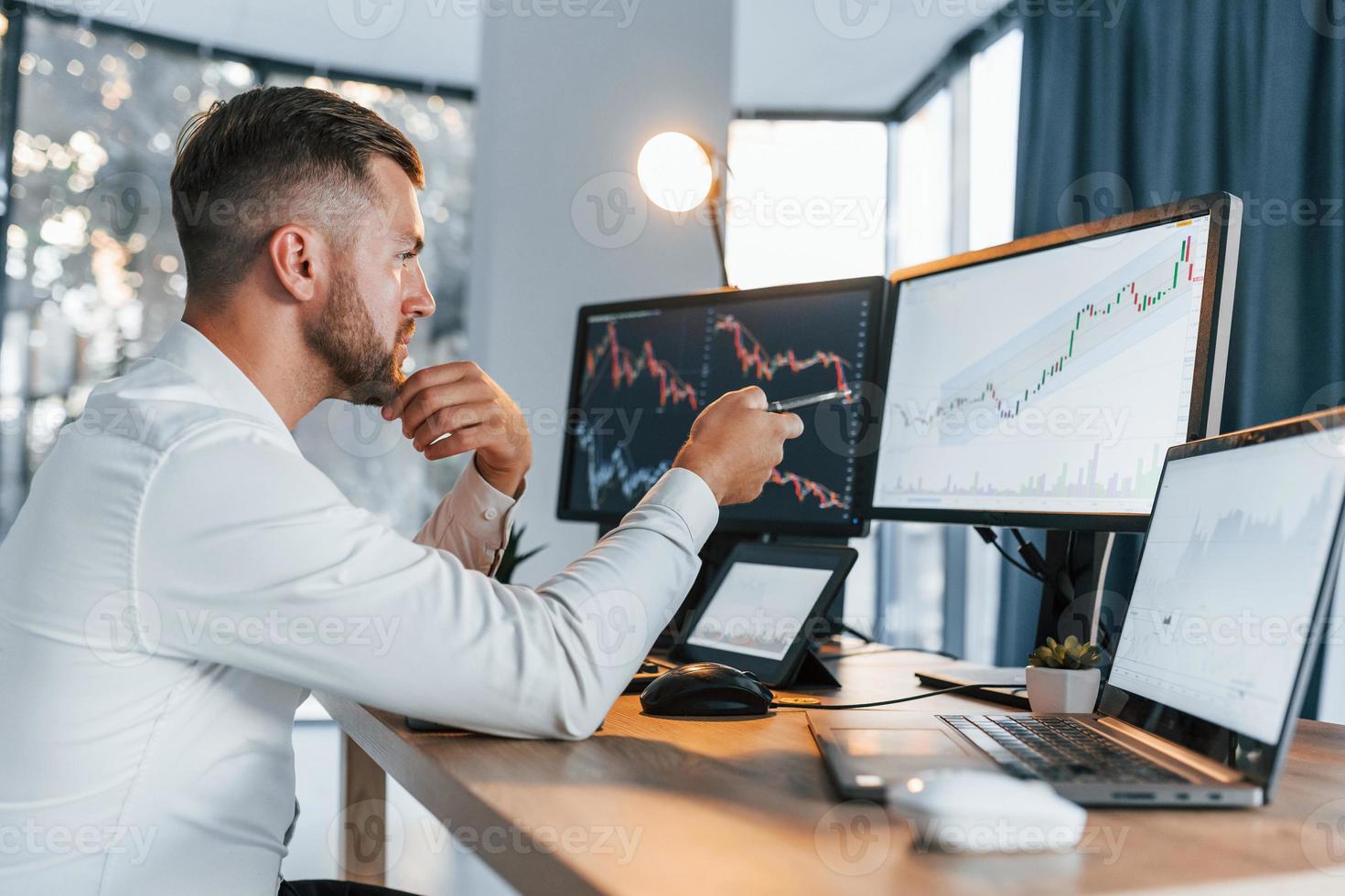 One person in the office. Young businessman in formal clothes is with multiple screens photo