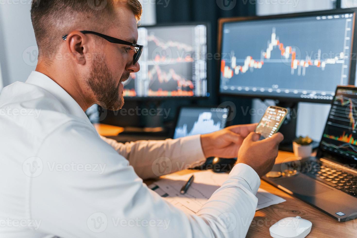 Many monitors. Young businessman in formal clothes is in office with multiple screens photo