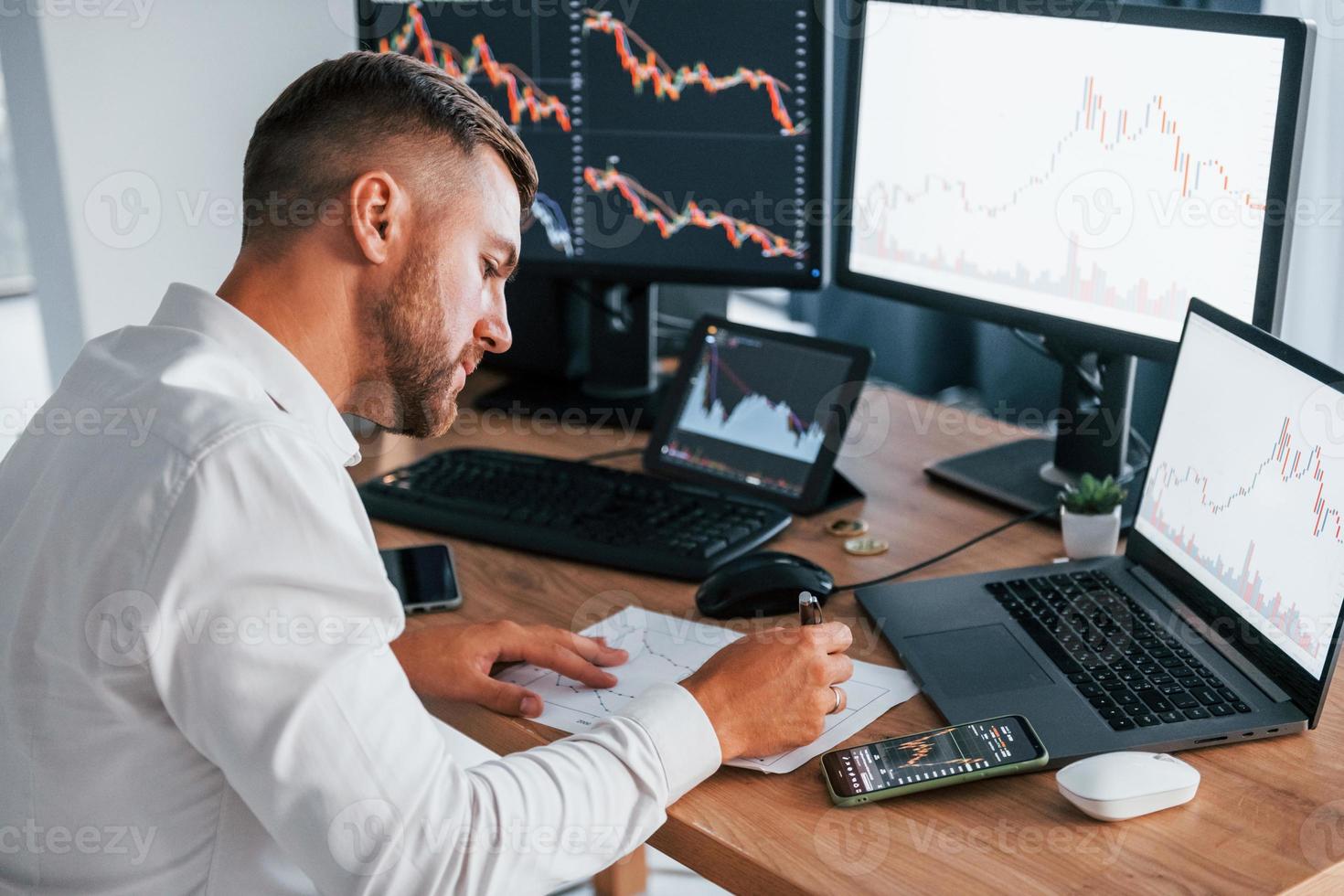 Modern technologies. Young businessman in formal clothes is in office with multiple screens photo