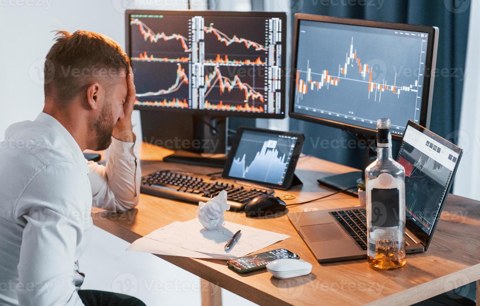 Conception of failure. Young businessman in formal clothes is in office with multiple screens photo