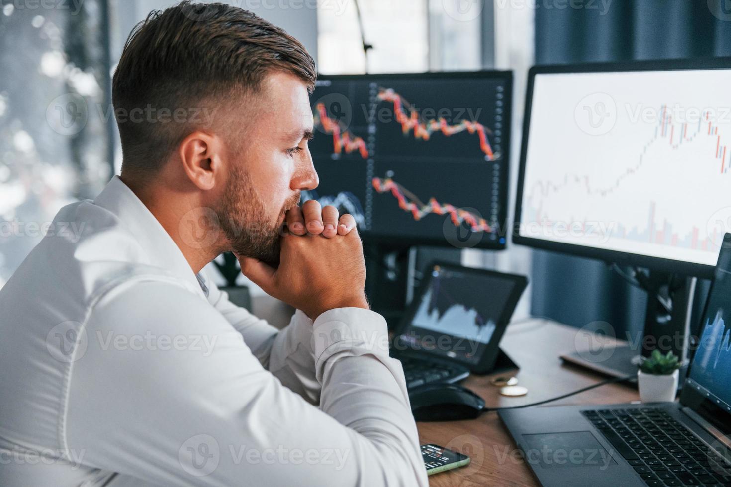 Focusing on the work. Young businessman in formal clothes is in office with multiple screens photo