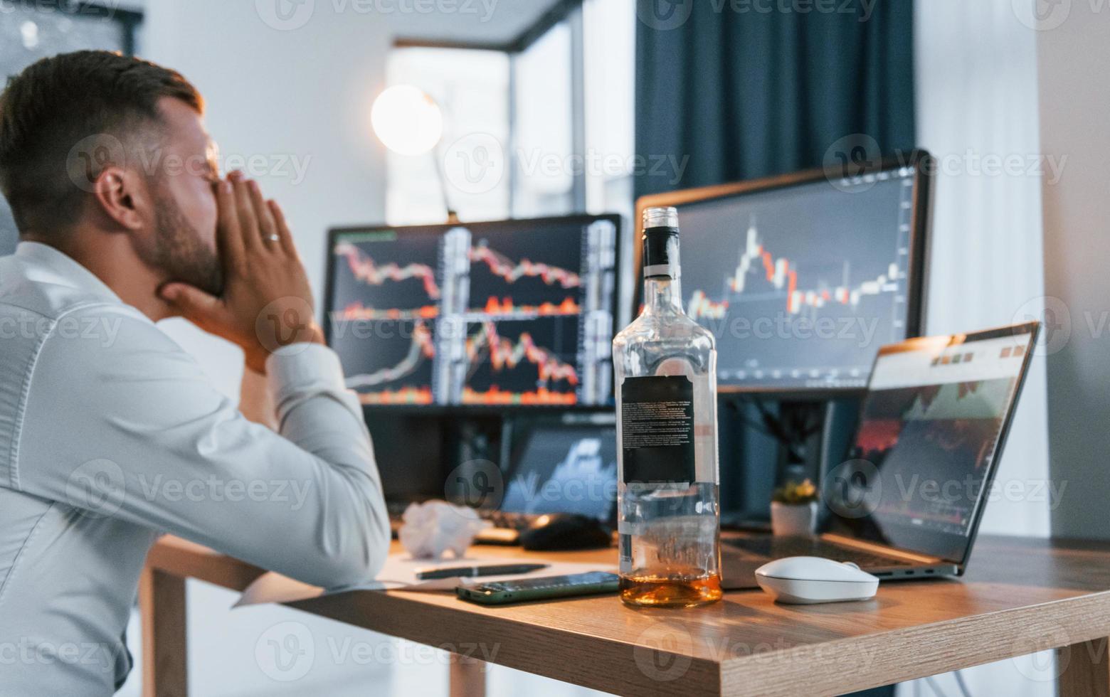 Conception of failure. Young businessman in formal clothes is in office with multiple screens photo